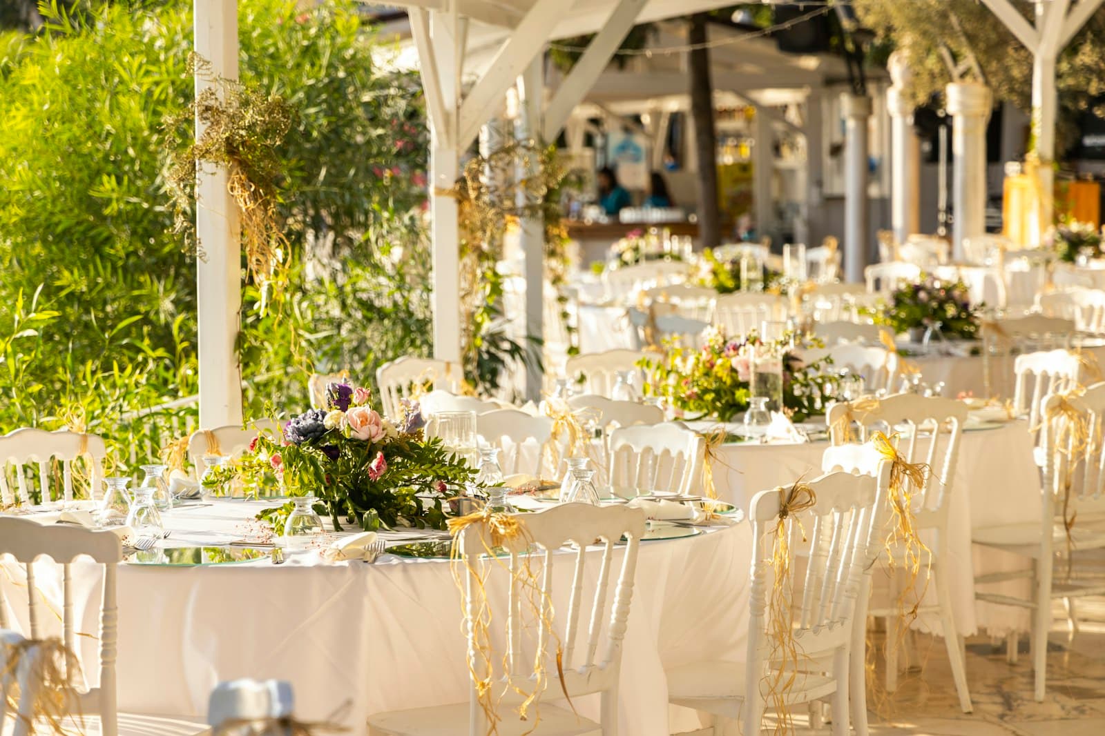 Sunlit reception tables with flowers, glassware and place settings